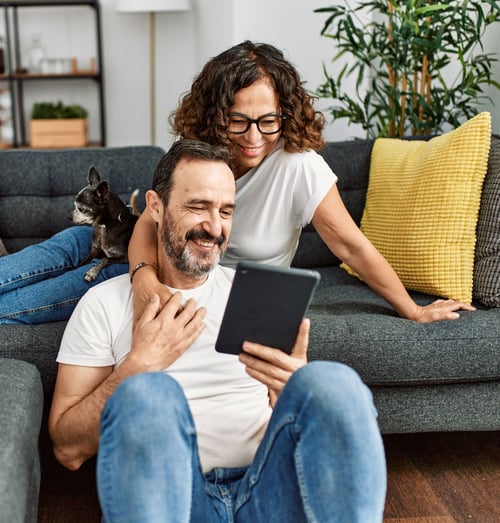 Mature couple sitting on the couch looking at tablet image